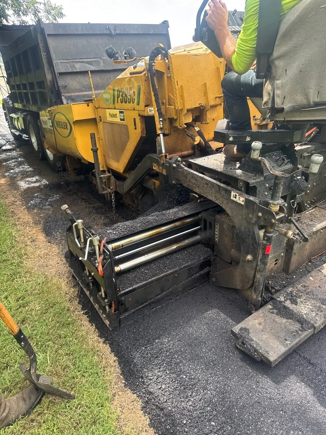 Hot asphalt being laid by the PavePro crew during active paving, representing the authority phase of the Hot Mix Method.