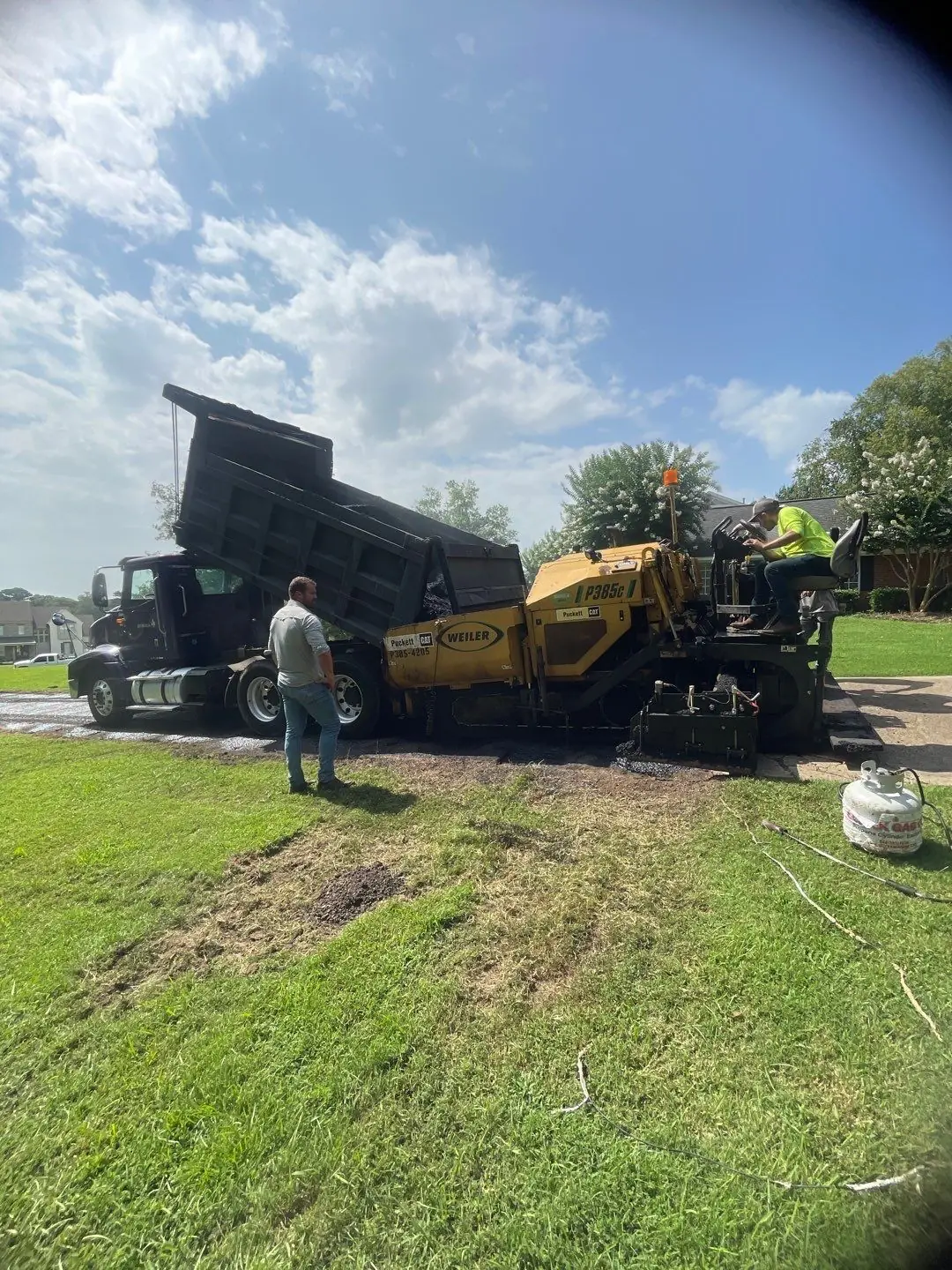 PavePro crew loading the paver at the start of a driveway job, representing the foundation phase of a paving project.